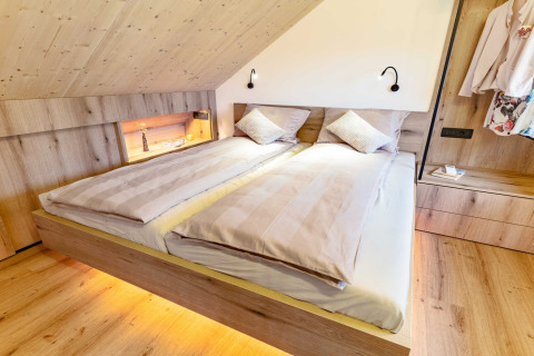Modern, cozy bedroom lodge in Slovenia featuring wood accents, double bed, and warm ambient lighting.