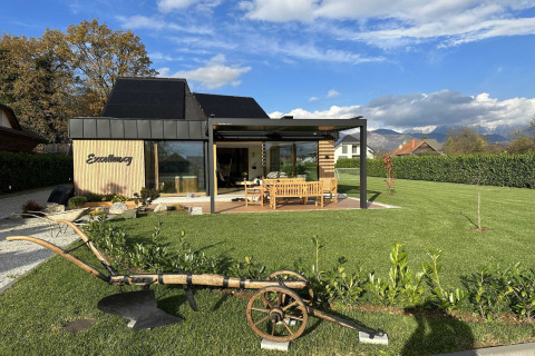 Modern lodge with spacious garden, outdoor seating area, and scenic mountain views in the background.