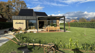 Lodge moderno con ampio giardino, area salotto all'aperto e vista sulle montagne sullo sfondo.