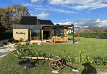 Lodge moderno con jardín amplio, zona de estar exterior y vistas panorámicas de montañas al fondo.