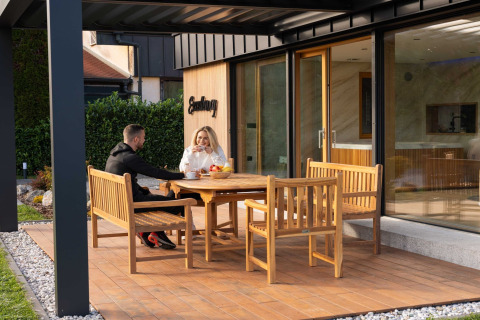 Two people enjoy drinks outside on the terrace at Elegant Warm Bliss Hideaway Escape Lodge in Slovenia.