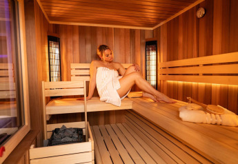 Donna che si rilassa nella sauna presso Elegant Warm Bliss Hideaway Escape Lodge in Slovenia, con telo.