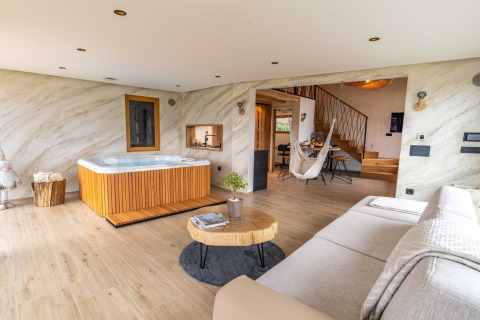 Elegant lodge in Slovenia featuring a hot tub, cozy living area, wooden floors, and contemporary decor.