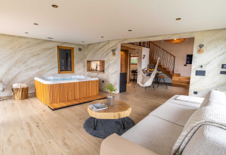 Elegant lodge in Slovenia featuring a hot tub, cozy living area, wooden floors, and contemporary decor.
