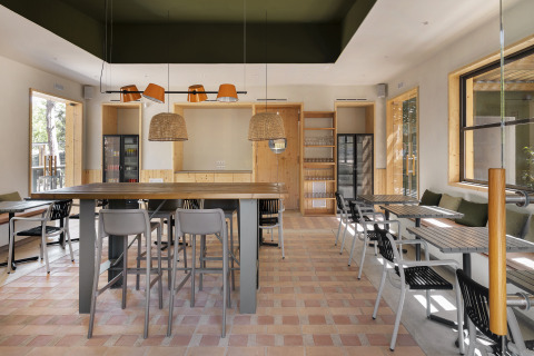 Modernes Café mit Holzakzenten und großen Fenstern im Wecamp Santa Cristina, Katalonien, Spanien.