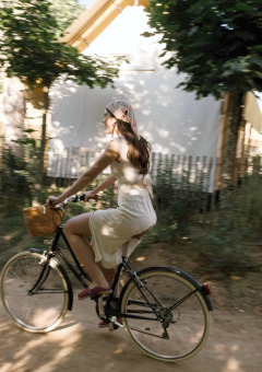 Donna con abito estivo in bicicletta con cestino al parco vacanze Wecamp Santa Cristina in Catalogna.