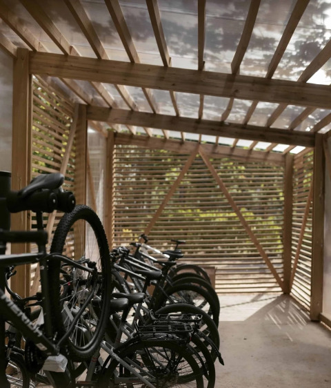 Houten fietsenstalling met geparkeerde fietsen bij Wecamp Santa Cristina, vakantiepark in Catalonië, Spanje.