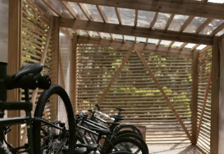 Abri à vélos en bois avec vélos garés au Wecamp Santa Cristina, parc de vacances en Catalogne, Espagne.