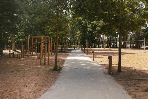 Weg durch einen baumbestandenen Bereich mit Holz-Fitnessgeräten im Wecamp Santa Cristina, Katalonien.