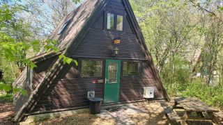 Chalet a forma di A con porta verde, tavolo da picnic fuori e natura intorno, presso Chalet no 142.