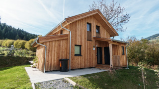 Chalet de madera en Kreischberg Chalets 29 rodeado de vegetación y cielo azul en un entorno natural tranquilo.