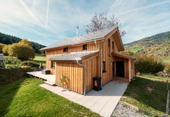 Chalet en bois à Kreischberg Chalets 29, Autriche, entouré de collines verdoyantes et d'une vue magnifique sur les montagnes.