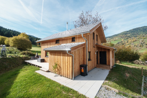 Holzchalet bei Kreischberg Chalets 29 in Österreich, umgeben von grünen Wiesen und Hügeln in einer Berglandschaft.