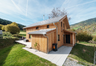 Holzchalet bei Kreischberg Chalets 29 in Österreich, umgeben von grünen Wiesen und Hügeln in einer Berglandschaft.