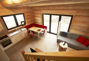 Interno dello Chalet «Faltri» in Austria: cucina, pareti in legno, zona pranzo d’angolo e divano.