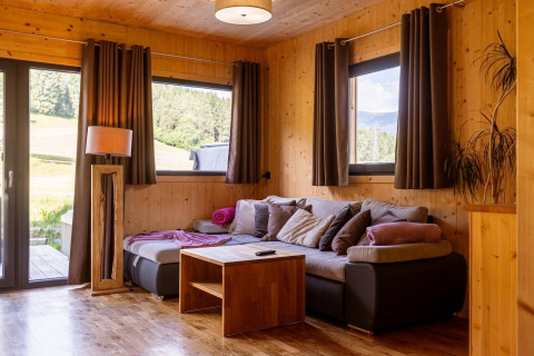 Gemütliches Wohnzimmer im Kreischberg Chalet 29 mit Holzwänden, Sofaecke und Naturblick.