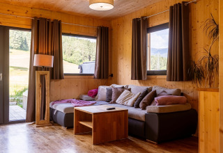 Gemütliches Wohnzimmer im Kreischberg Chalet 29 mit Holzwänden, Sofaecke und Naturblick.