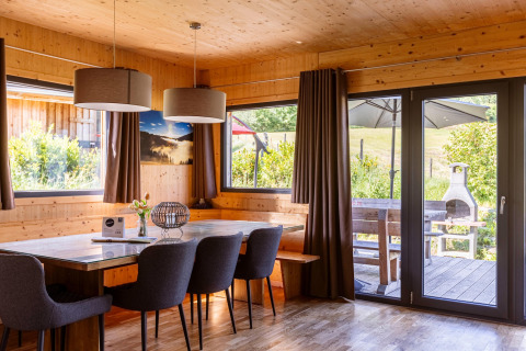 Essbereich in einem Chalet mit Holzwänden, großen Fenstern und Blick auf eine Terrasse in Österreich.