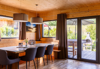 Essbereich in einem Chalet mit Holzwänden, großen Fenstern und Blick auf eine Terrasse in Österreich.