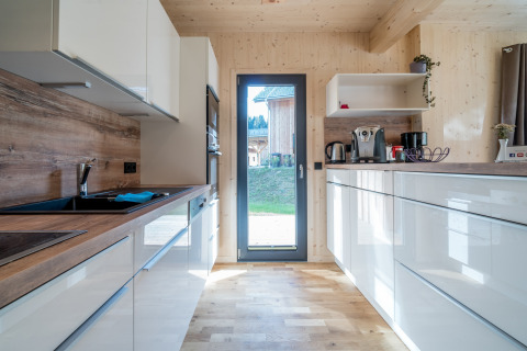 Modernes Holzküche mit weißen Schränken im Kreischberg Chalets 29, Österreich, Tageslicht einfallend.