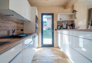 Modernes Holzküche mit weißen Schränken im Kreischberg Chalets 29, Österreich, Tageslicht einfallend.