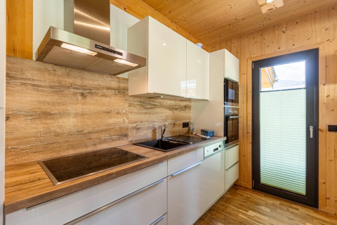 Modernes Kücheninterieur mit Holzverkleidung, weißen Schränken und Geräten im Kreischberg Chalets 29, Österreich.