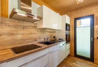 Modernes Kücheninterieur mit Holzverkleidung, weißen Schränken und Geräten im Kreischberg Chalets 29, Österreich.