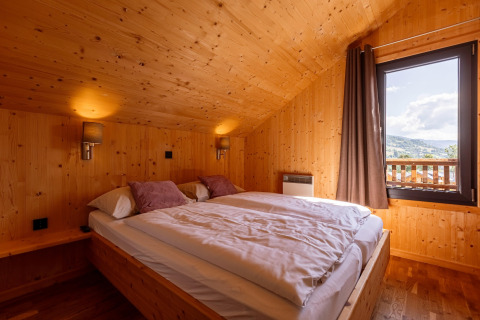 Gemütliches Schlafzimmer mit Holzwänden und Doppelbett, Kreischberg Chalets 29, Österreich, Bergblick.