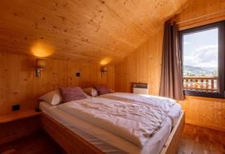 Gemütliches Schlafzimmer mit Holzwänden und Doppelbett, Kreischberg Chalets 29, Österreich, Bergblick.