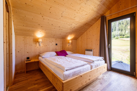 Schlafzimmer im Kreischberg Chalets 29 in Österreich mit Holzwänden, Doppelbett und Naturblick.