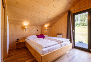 Schlafzimmer im Kreischberg Chalets 29 in Österreich mit Holzwänden, Doppelbett und Naturblick.