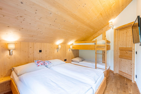 Modernes Schlafzimmer mit Doppelbett und Etagenbett aus Holz in den Kreischberg Chalets 29, Österreich.