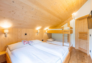 Modernes Schlafzimmer mit Doppelbett und Etagenbett aus Holz in den Kreischberg Chalets 29, Österreich.