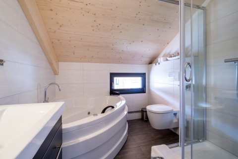 Modernes Badezimmer im Kreischberg Chalets 29 in Österreich mit Eckbadewanne, Glasdusche und schräger Decke.