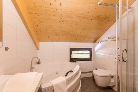 Modernes Bad mit Holzdecke, Eckbadewanne, Dusche und WC im Kreischberg Chalets 29 in Österreich.
