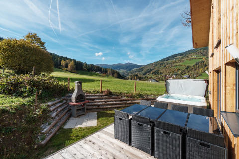 Terrasse des Kreischberg Chalets 29 in Österreich mit Whirlpool, Grillplatz und Ausblick auf Berge.