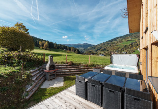 Terrasse des Kreischberg Chalets 29 in Österreich mit Whirlpool, Grillplatz und Ausblick auf Berge.