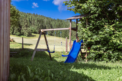 Spielplatz mit Rutsche und Schaukeln bei Kreischberg Chalets 29, umgeben von Natur in Österreich.