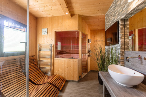 Modernes Wellnesszimmer im Kreischberg Chalets 29, Österreich, mit Sauna, Liegestühlen und Waschtisch.