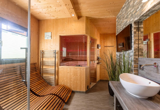 Modernes Wellnesszimmer im Kreischberg Chalets 29, Österreich, mit Sauna, Liegestühlen und Waschtisch.