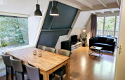 Modernes Wohnzimmer im Chalet Nr. 142 in Belgien mit Esstisch, Sofa, TV und Blick ins Grüne.