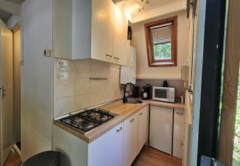Kleine Küche im Chalet 'no 142' in Belgien mit Gasherd, Spüle, Mikrowelle und Fensterblick.