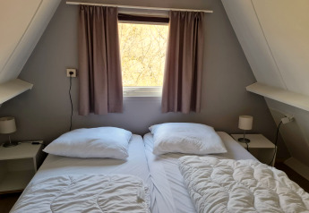 Gemütliches Schlafzimmer im Chalet Nr. 142 in Belgien mit zwei Betten, Fenster und Nachttischen.
