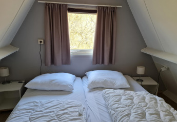 Gemütliches Schlafzimmer im Chalet Nr. 142 in Belgien mit zwei Betten, Fenster und Nachttischen.