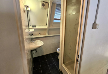 Et lille badeværelse i Chalet no 142 Belgien med brusekabine, håndvask, toilet og vindue.