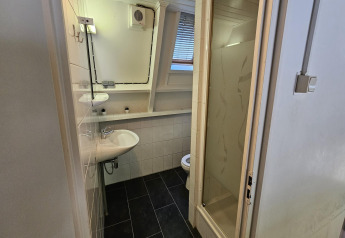 Kleines Badezimmer im Chalet no 142 Belgien mit Dusche, Waschbecken, WC und Fenster.