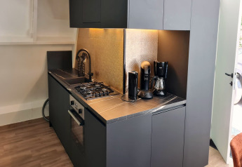 Moderne tekøkken i Chalet no 186 i Belgien med sort indretning, kaffemaskiner og gaskomfur.