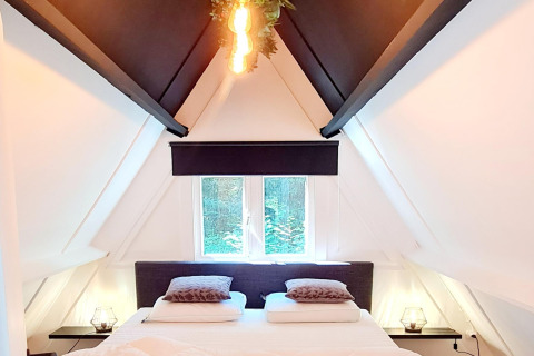 Helles Schlafzimmer im Chalet no 186 Belgien, mit Dachschrägen, Doppelbett und moderner Beleuchtung.