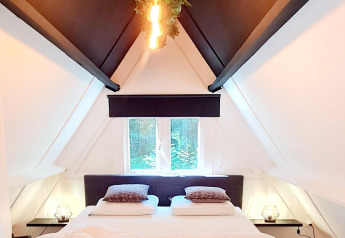Helles Schlafzimmer im Chalet no 186 Belgien, mit Dachschrägen, Doppelbett und moderner Beleuchtung.