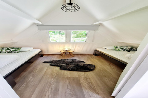 Helles Schlafzimmer im Chalet no 186 in Belgien mit zwei Einzelbetten, Fenstern und Holzdekor.
